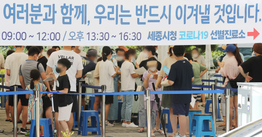 코로나19의 비수도권 확산세가 무섭게 이어지고 있는 가운데 5일 오후 세종시 세종시청에 마련된 선별진료소에 검사를 받으려는 시민들이 부채로 더위를 식히며 순서를 기다리고 있다.   연합뉴스